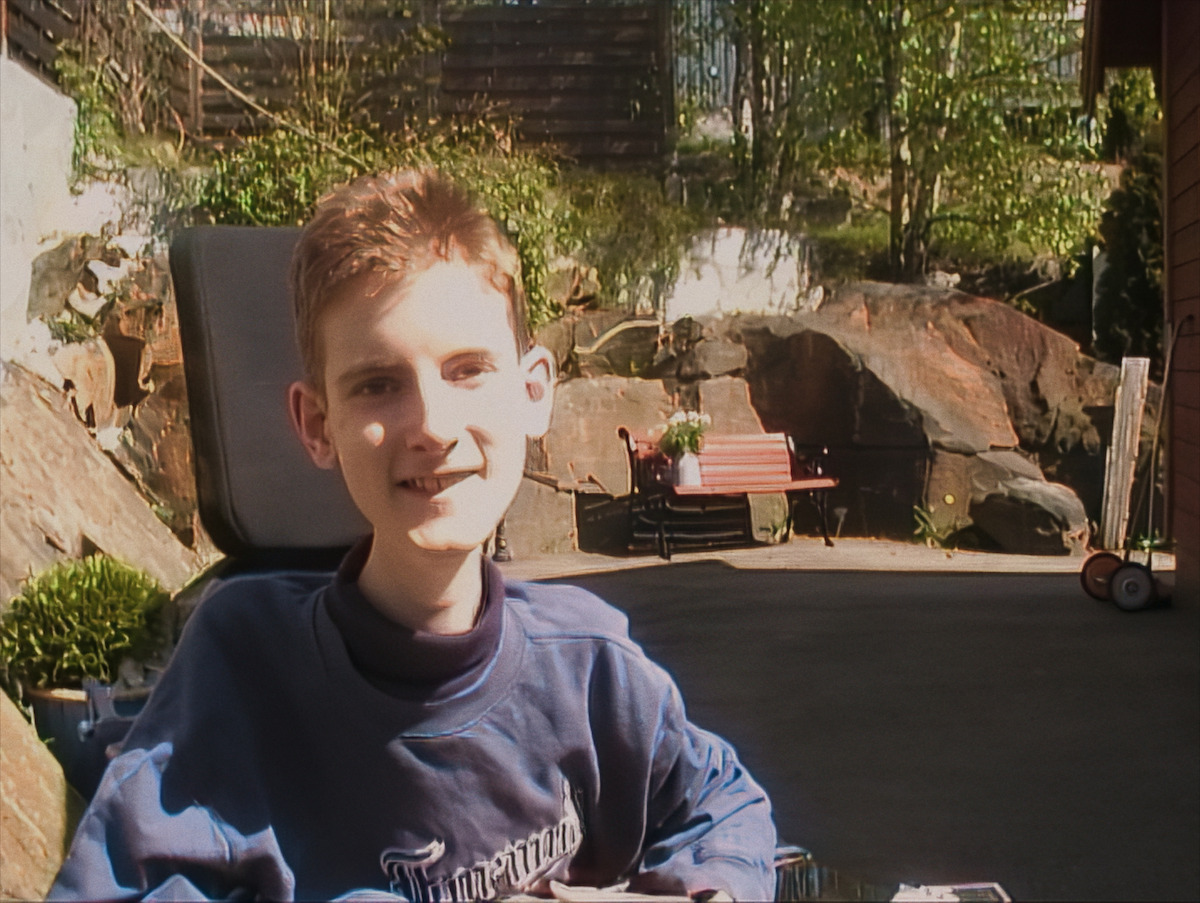 Mat Steen wears a blue sweatshirt and sits in a wheelchair in a lovely outdoor patio.