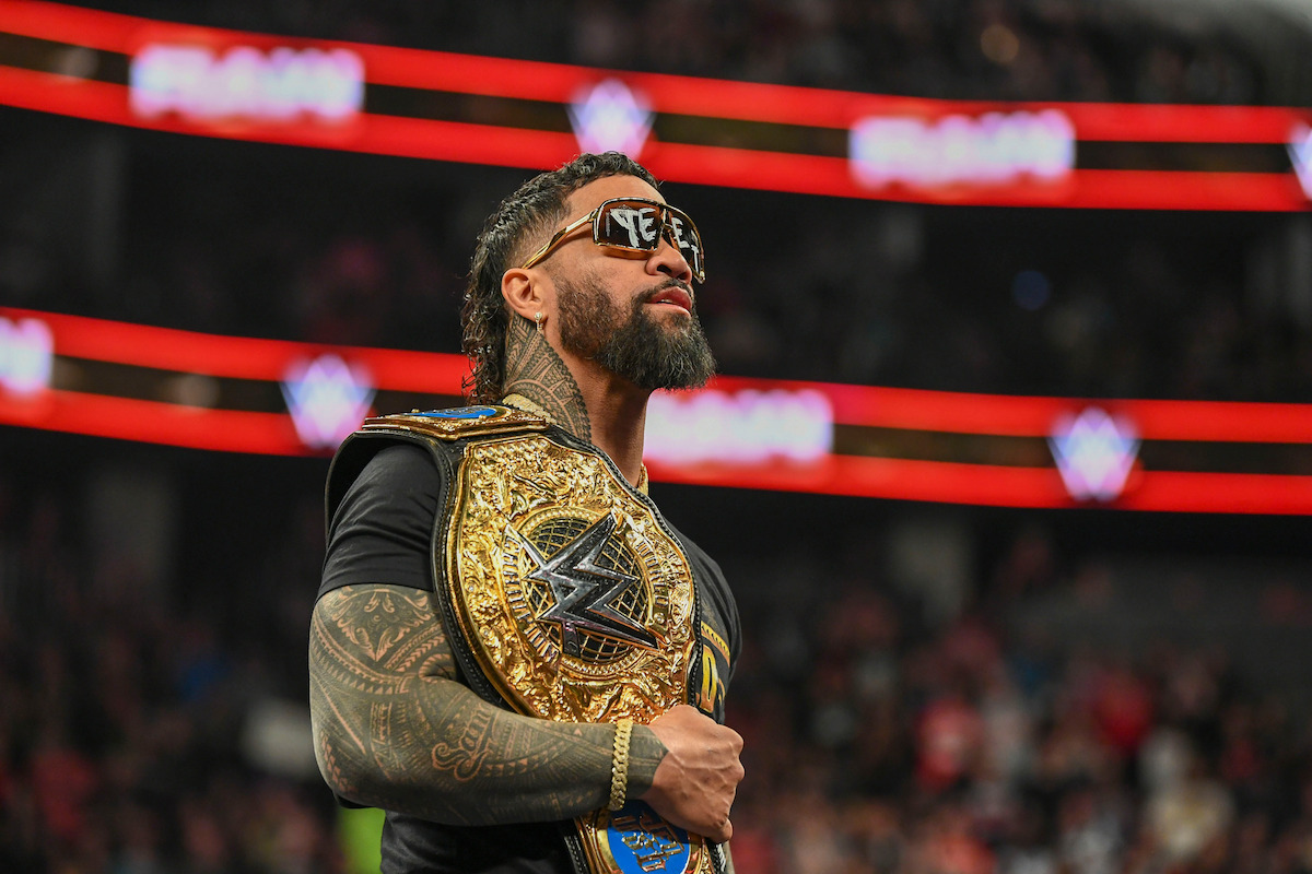 Jey Uso holding his belt as he looks on at the crowd.