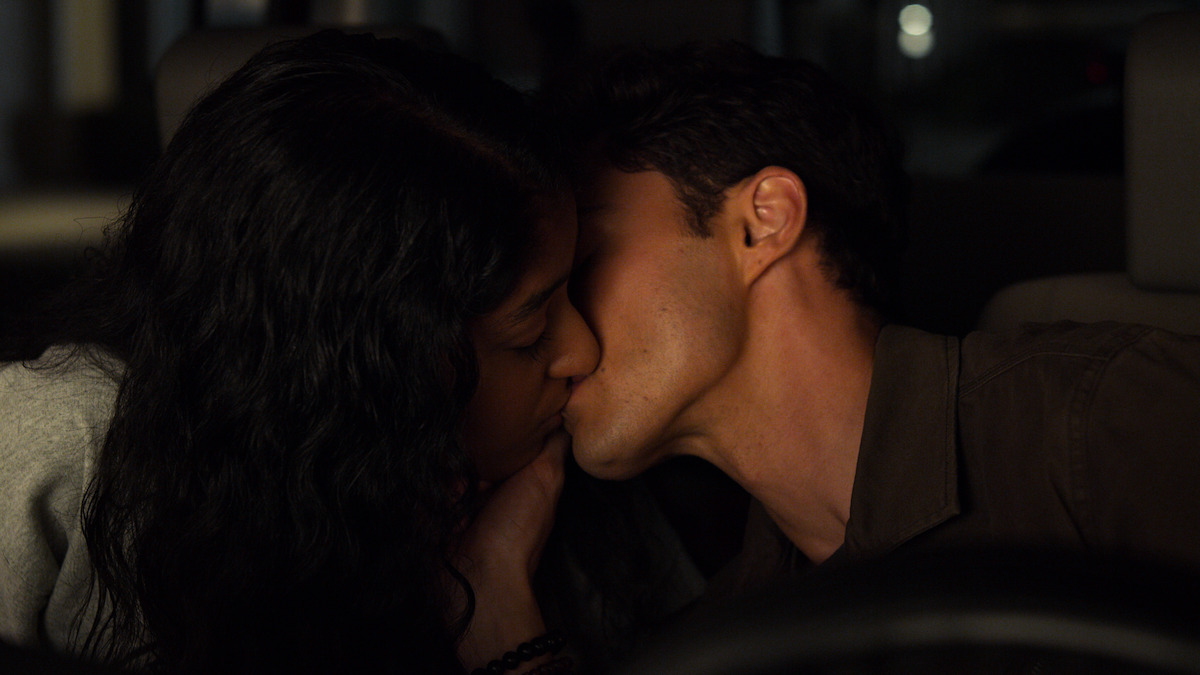 Two people share a romantic kiss inside a dimly lit car at night, suggesting an intimate and private moment.