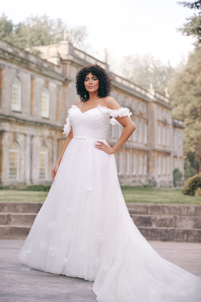 Woman in bridal dresses poses and looks off into the distance.