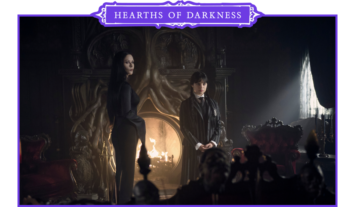 Catherine Zeta-Jones as Morticia Addams and Jenna Ortega as Wednesday Addams stand in front of a fireplace in ‘Wednesday’ Season 2.