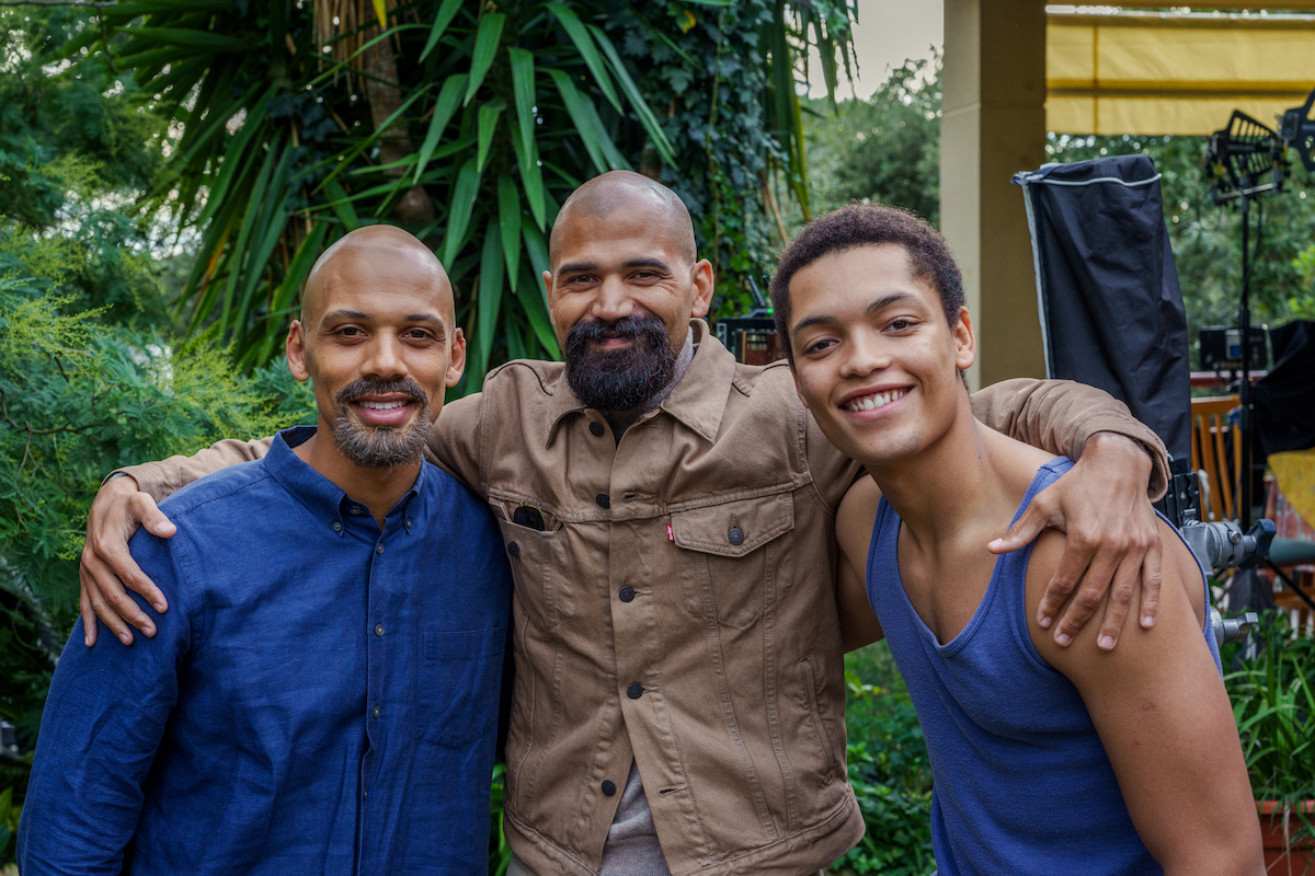 A group of three men pose together.