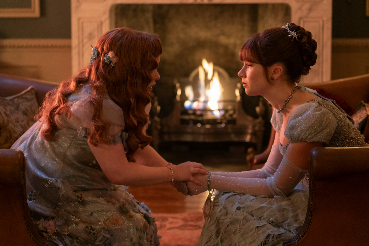 Nicola Coughlan as Penelope Featherington and Claudia Jessie as Eloise Bridgerton face each other holding hands in Season 3 of ‘Bridgerton.’