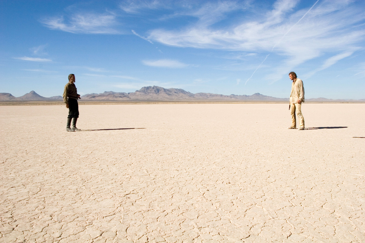 Pierce Brosnan as Gideon and Liam Neeson as Carver face off on a salt flat in a still image from ‘Seraphim Falls’