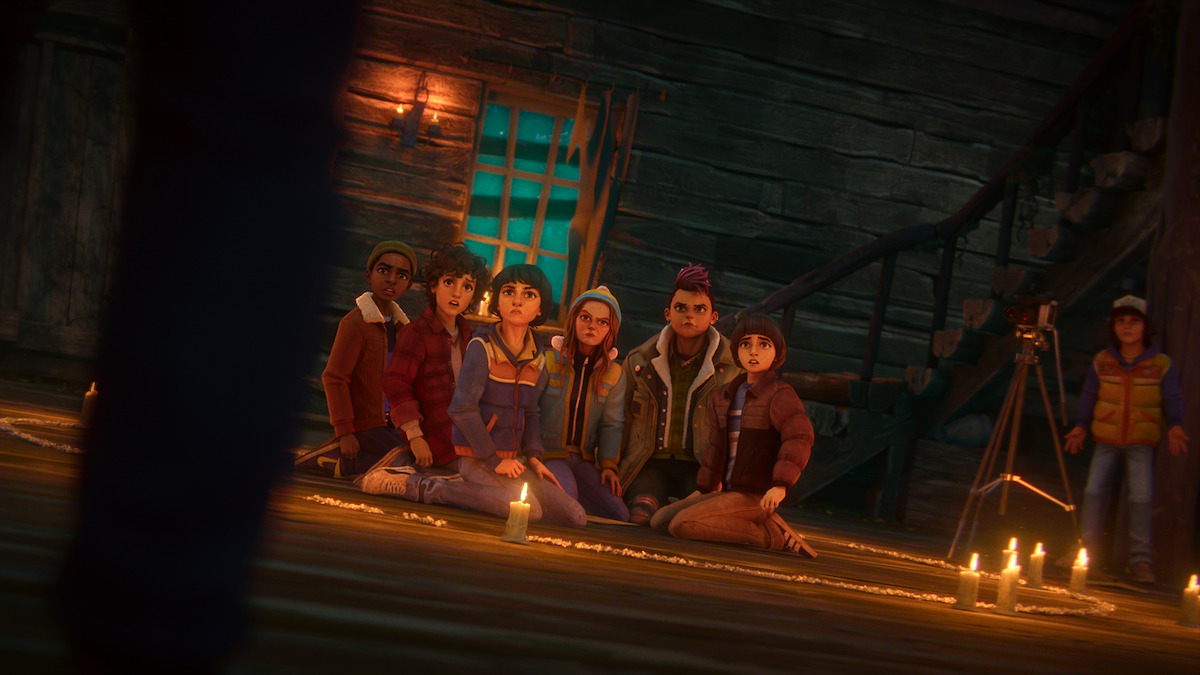 Six animated teens sit together on a wooden floor in a dim, candle-lit cabin, looking up at a mysterious figure. Candles, a camera on a tripod, and a spiral drawn on the floor set a tense, supernatural scene.
