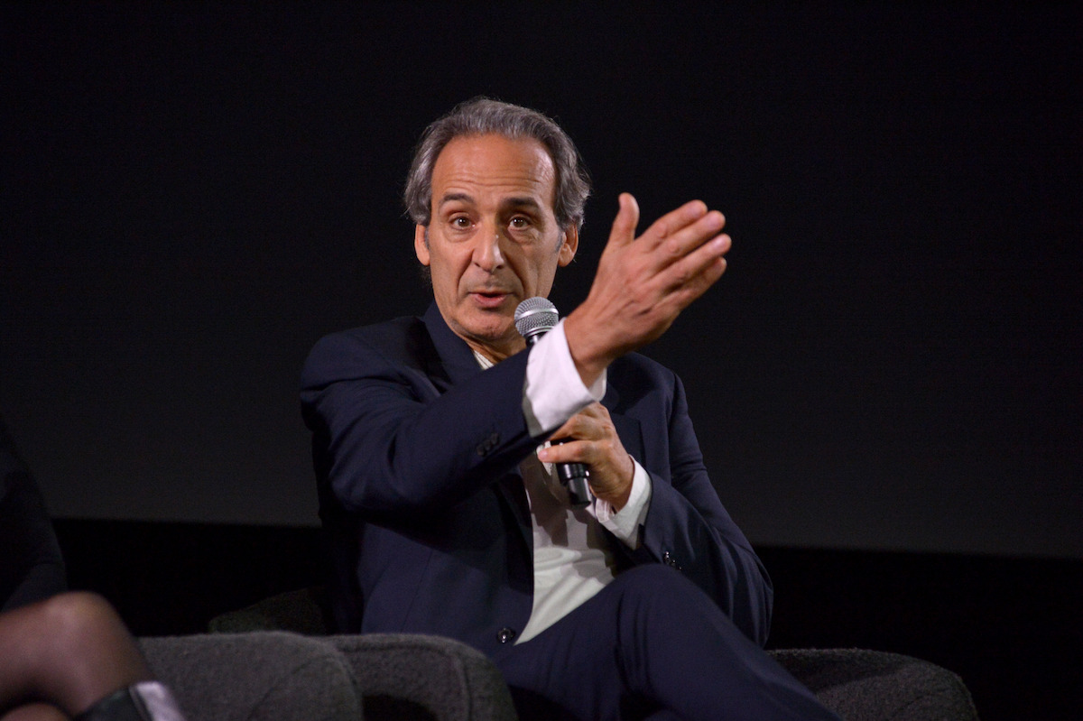 Alexandre Desplat holds a microphone.