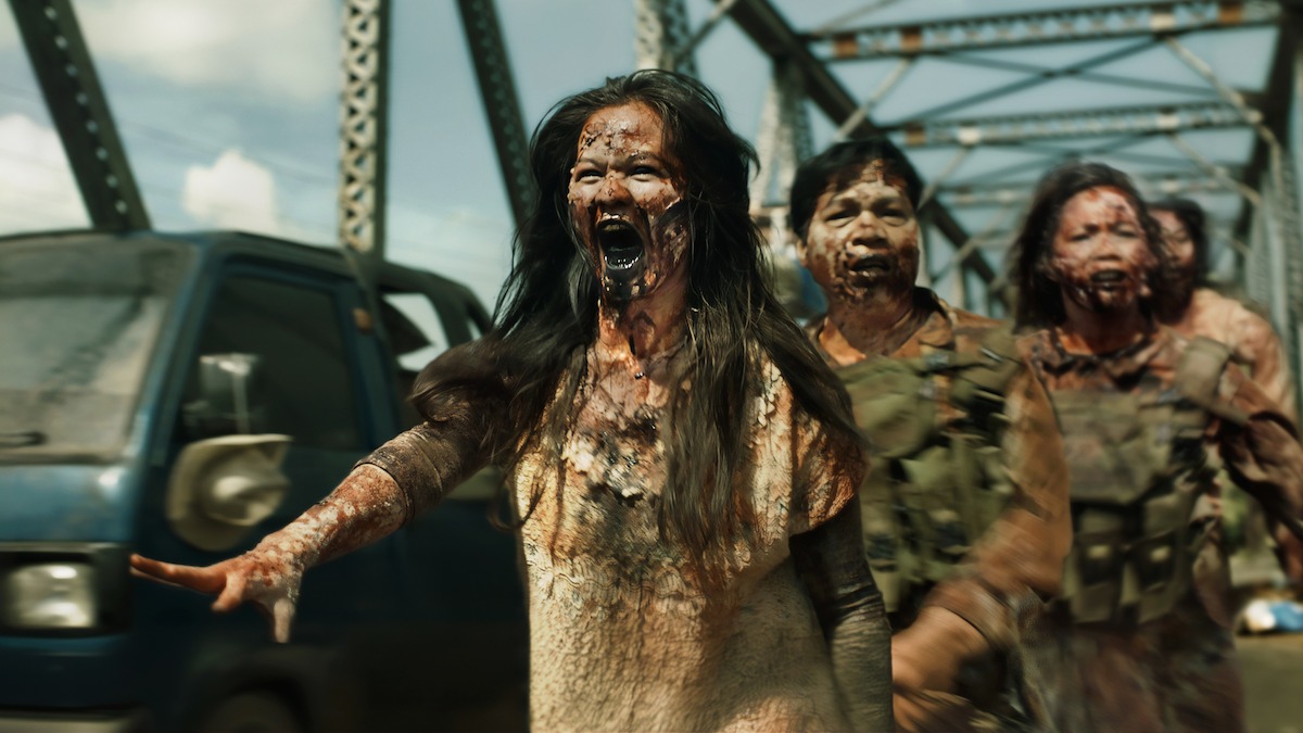 In an image from the film “Outside,” bloody zombies in tattered clothing run across a bridge.