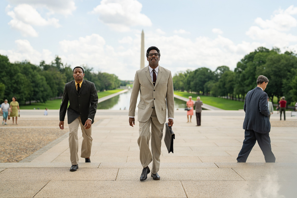 Colman Domingo walks toward the Lincoln Memorial with the Washington Monument behind him in a still from ‘Rustin.’