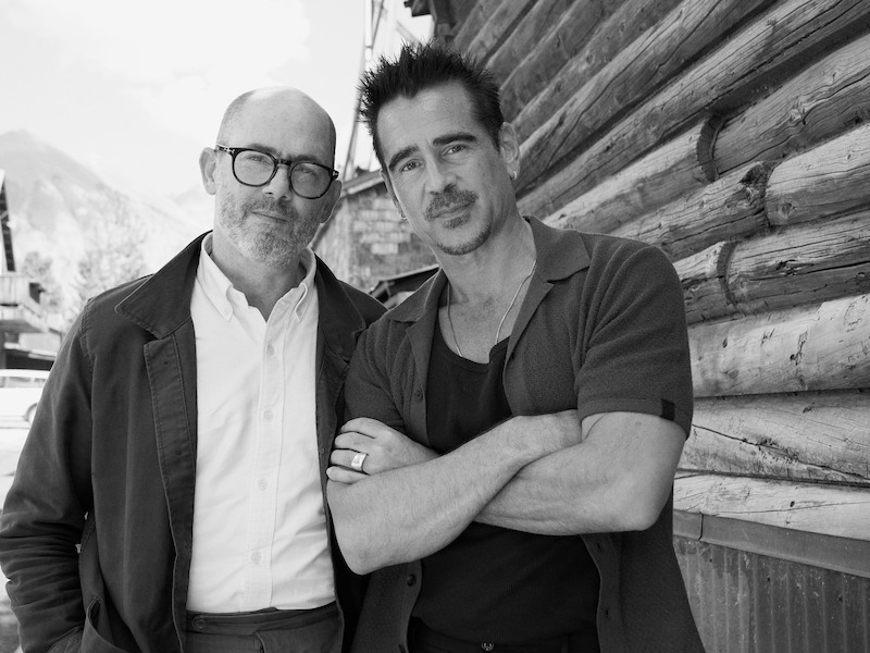 Edward Berger, in a dark jacket and white shirt, and Colin Farrell, in a gray shirt post in front of a building.