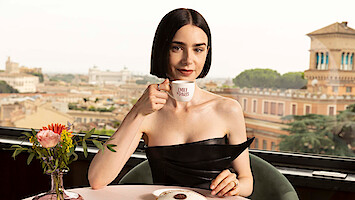 Lily Collins holds a teacup that reads 'Emily in Paris'