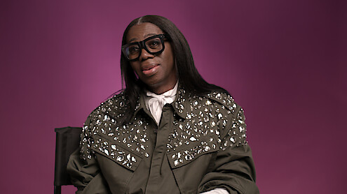 J. Alexander aka Miss J sitting in front of a plum background