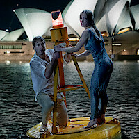 Glen Powell and Sydney Sweeney stand on a buoy in the Sydney Harbor