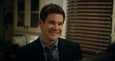 Adam Devine smiles in a kitchen in a still from 'The Out-Laws.'