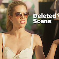 Alexandra Jarvis wearing sunglasses with her left hand raised.