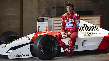 Gabriel Leone as Ayrton Senna sits on the side of his race car in 'Senna'