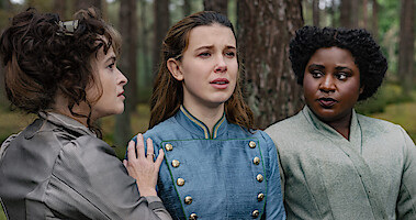 Enola standing in the middle of 2 others