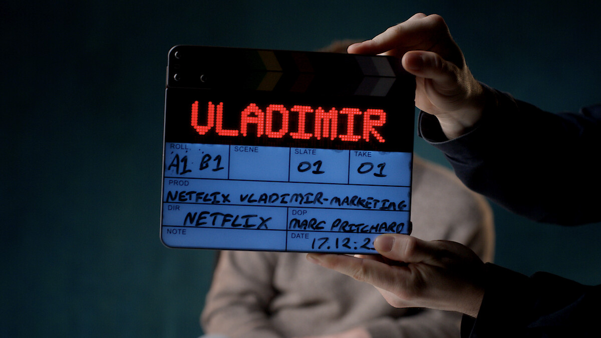 Clapperboard with "VLADIMIR" illuminated, held in front of a blurred person on a dark set, showing film production details for a Netflix project.