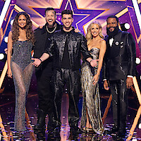 Chrissy Teigen, Jelly Roll, TJ Salta, Sarah Michelle Gellar, and Anthony Anderson dressed in sparkling outfits stand smiling together on a stage with a star-shaped backdrop and dramatic purple lighting, confetti on the floor, and a festive atmosphere