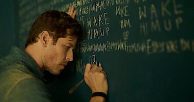 Josh Dallas as Ben Stone in Manifest Season 4 writes on chalkboard.