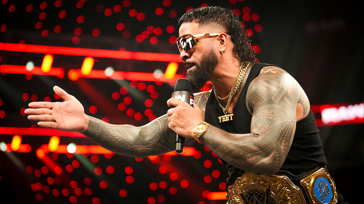 Jey Uso talking into a microphone while wearing his belt in the ring