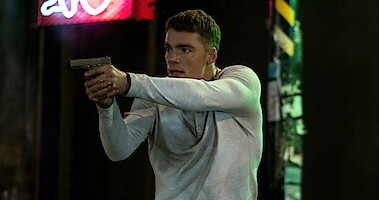 Gabriel Basso as Peter Sutherland holding a gun in The Night Agent Season 1