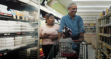 Barack Obama walks with a worker in a grocery store. 