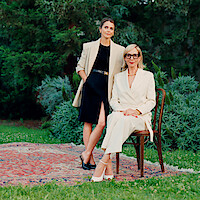 Keri Russell, standing, and Allison Janney, sitting in a chair in an outdoor space. 
