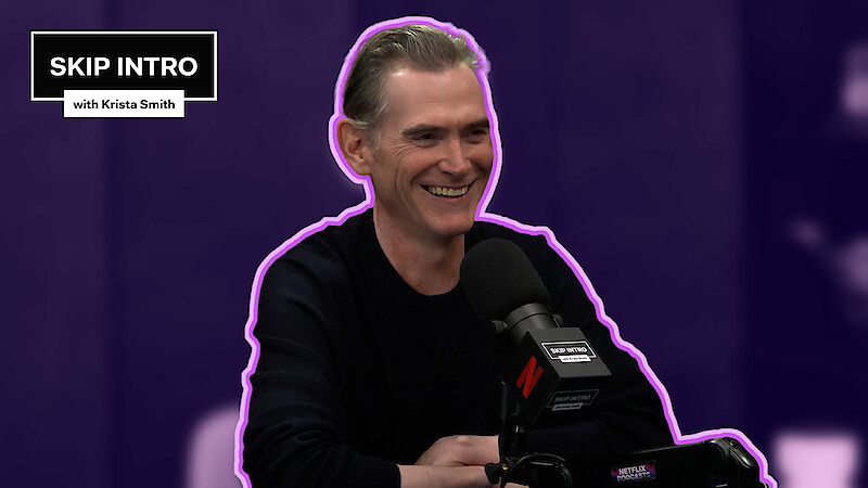 Billy Crudup sits smiling in front of a microphone during a podcast recording for "Skip Intro with Krista Smith." The background is purple, and the podcast logo appears in the top left corner.