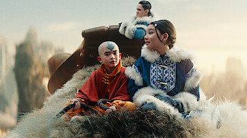 Gordon Cormier as Aang, Kiawentiio as Katara, and Ian Ousley as Sokka, ride Appa, a flying air bison, in Season 1 of 'Avatar: The Last Airbender'
