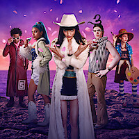 Five people in colorful, eccentric outfits pose on rocky ground under a purple sky with pink petals, suggesting a whimsical, artistic, and fantastical setting with strong individual personalities and creative elements.