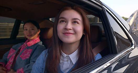 Kitty looks hopefully out of a car window next to Yuri