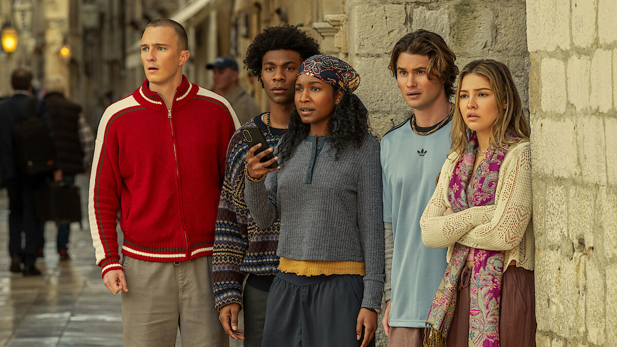 Photo: netflix.com Five young adults stand together against a stone wall on a city street, looking ahead with focused and concerned