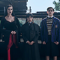 Catherine Zeta-Jones as Morticia Addams, Jenna Ortega as Wednesday, and Isaac Ordonez aș Pugsley Addams stand in front of their car in Season 2 of ‘Wednesday’