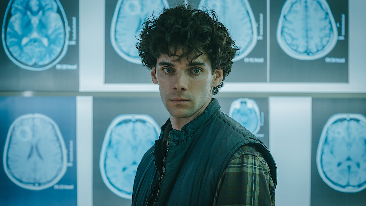 Álvaro Rico as Elmer stands in front of brain scans at a medical facility in an image from 'The Gardener.'