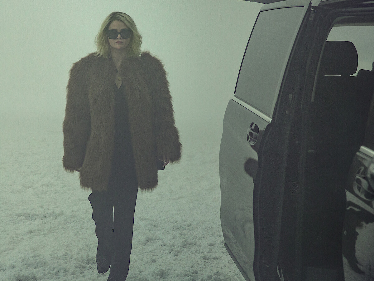 Jessi (Selena Gomez) wears a fur jacket and walks through the snow.
