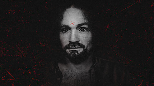 A man with curly hair and a beard stares intensely at the camera, set against a dark, gritty background. He has a red X marked on his forehead and visible chest hair, wearing an open shirt. The overall mood is eerie and dramatic.