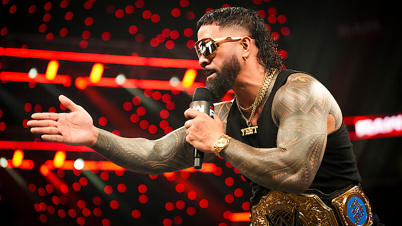 Jey Uso talking into a microphone while wearing his belt in the ring