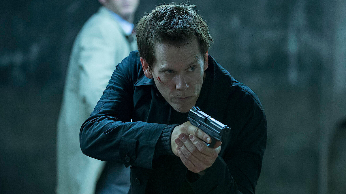 Kevin Bacon as Special Agent Ryan Hardy points a gun at a suspect in 'The Following.'