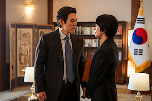 Sul Kyung-gu as Park Dong-ho and Kim Hee-ae as Jeong Su-jin face off in an office.