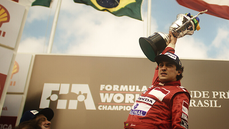 Gabriel Leone as Ayrton Senna lifts a large trophy in 'Senna'
