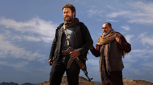 Gerard Butler stands in front of a man in an image from the movie 'Kandahar.'