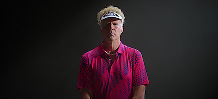 Will Ferrell as The Hawk poses in a pink golf shirt and white visor.
