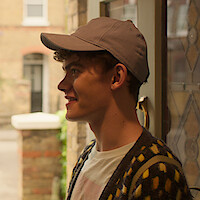 Joe Locke as Charlie wears a baseball cap in Season 3 of 'Heartstopper'