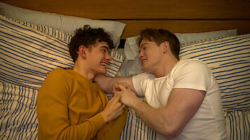 Joe Locke as Charle and Kit Connor as Nick cuddle together in bed in Season 3 of 'Heartstopper.'