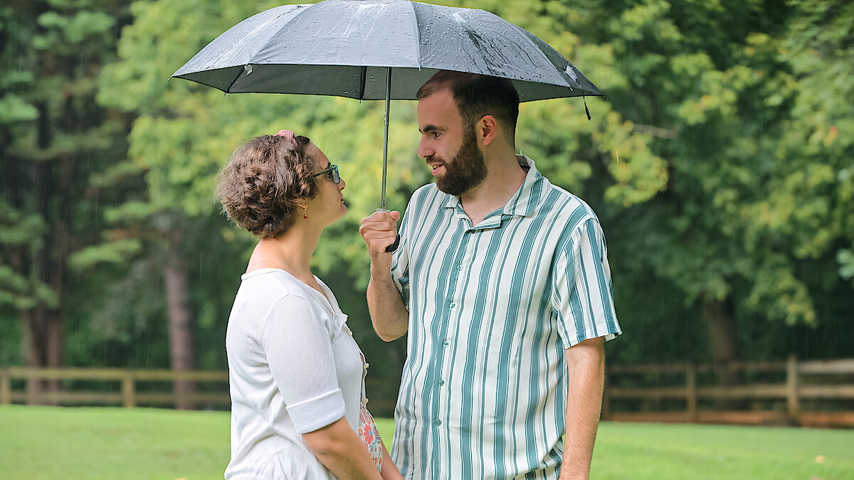 Connor holds an umbrella over his date