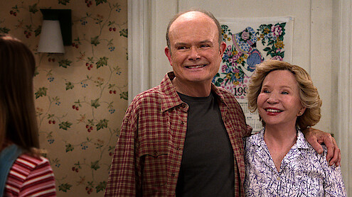 Kurtwood Smith as Red and Debra Jo Rupp as Kitty stand in their kitchen smiling in Part 2 of 'That '90s Show'