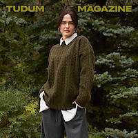 Zoey Deutch stands against a backdrop of trees