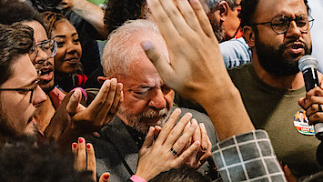 A crowd surrounds a man praying.
