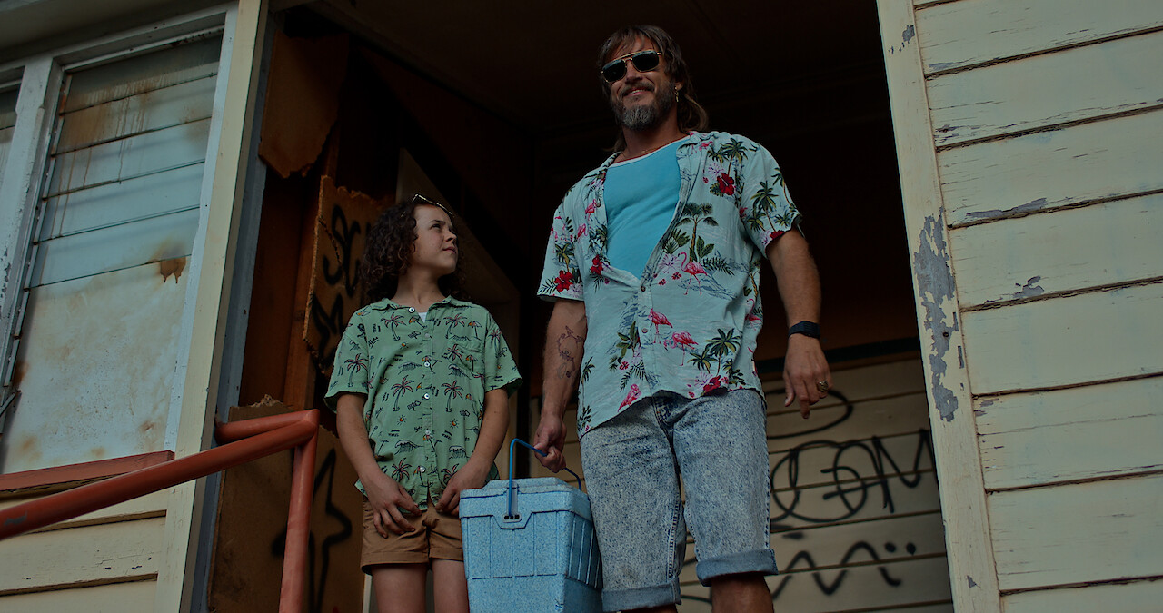 two people standing on the porch of a dilapidated house. 