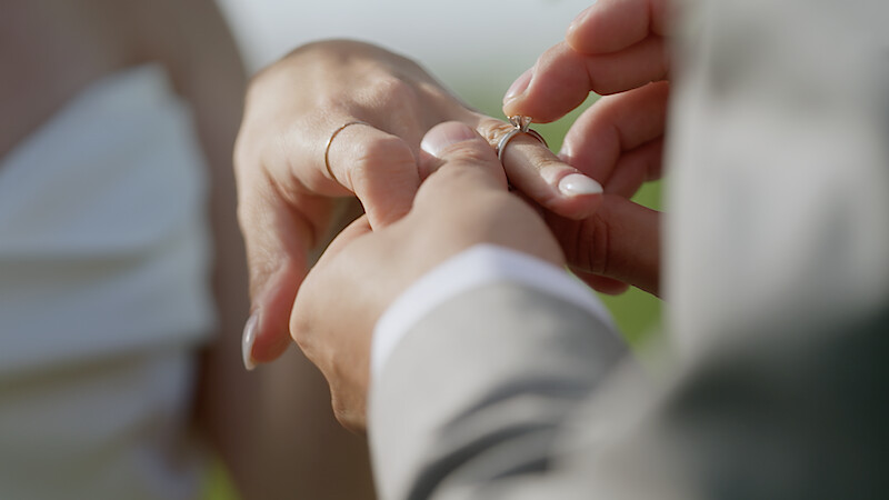A man puts a ring on a woman's finger.